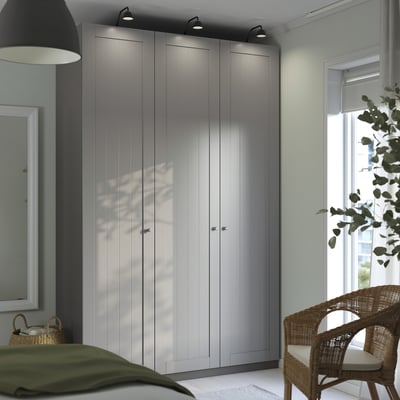 Modern bedroom with grey PAX wardrobe, spotlights, window, wicker chair, and lamp.