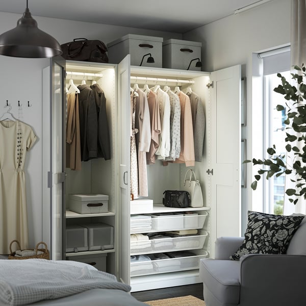 Open wardrobe with mirror doors, clothes hangers, lit shelves, drawers, baskets, and storage boxes for organised bedroom storage.