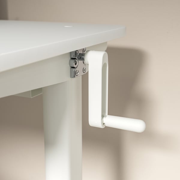 White crank handle on adjustable white desk, metal screws visible.