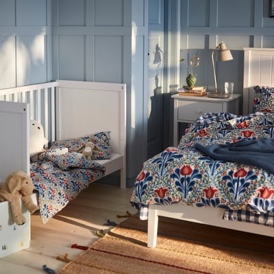 Blue & red floral SÄTERVIDE duvet on single bed, matched smaller bed, wooden floor, blue walls.