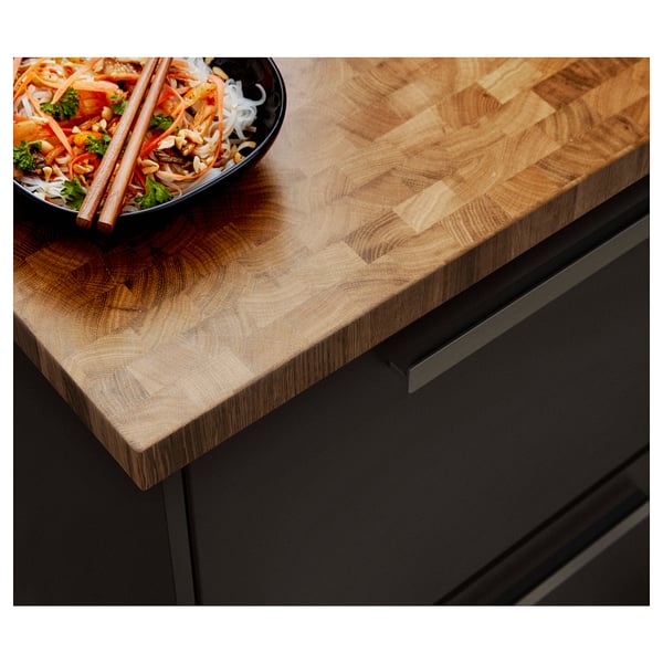 Wooden SKOGSÅ countertop with food bowl, light brown grain, dark cabinets.
