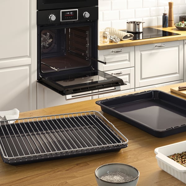 Modern kitchen with open oven displaying adjustable racks, baking trays, and a bowl of rice on the counter.