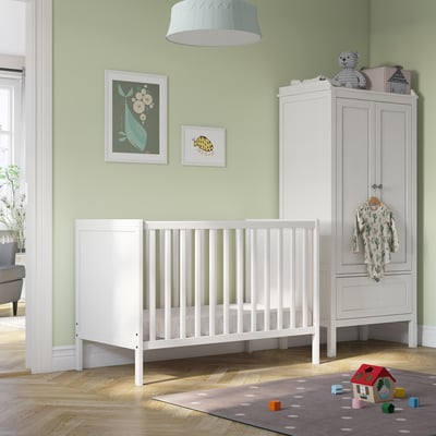 SUNDVIK crib, low base, removable side, beside tall wardrobe with baby clothes. Light green room, colorful art, rug with playhouse toy.