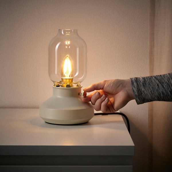 Hand turning dimmer on TÄRNABY lamp, adjusting warm, soft light.
