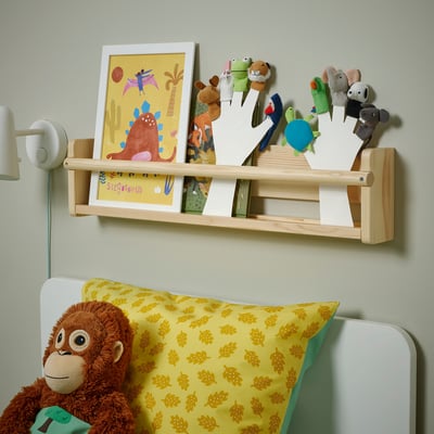 Wooden shelf with books, puppets, and childrens toys above bed.