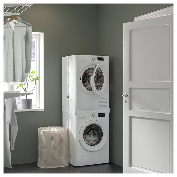 Modern laundry setup with stacked white washing machine and dryer by door.