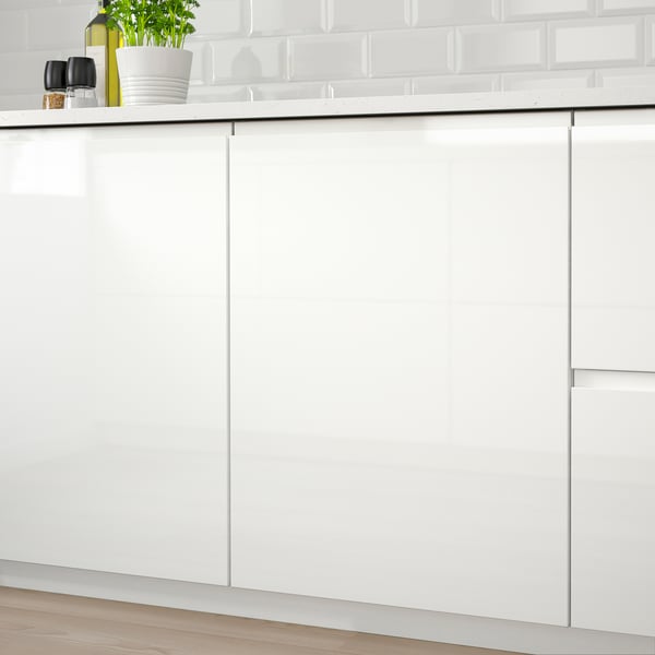 White high-gloss kitchen cabinets with integrated handles, creating a modern, sleek look. The glossy surface ensures easy cleaning.