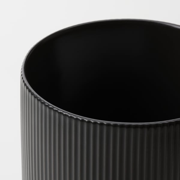Черная ваза с вертикальными бороздками на белом фоне.