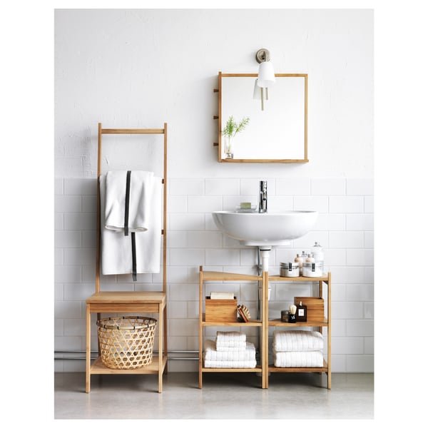 Минималистичная сцена в ванной комнате с деревянным стулом RÅGRUND, белой раковиной, зеркалом и сложенными полотенцами.