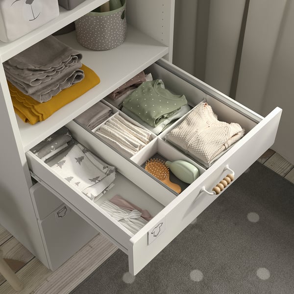 Открытый белый ящик с детской одеждой и предметами, организованный по отделениям.