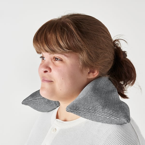 A person hold a microwavable heating pad on the person shoulder for neck and shoulder relief.