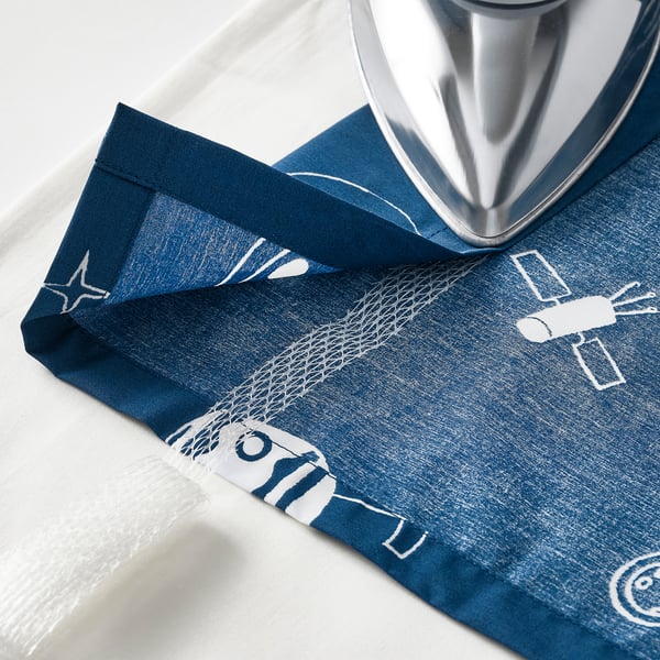 Curtains with glow-in-dark space pattern being ironed. Includes touch fastener for easy opening and adjustable length with iron-on hem.