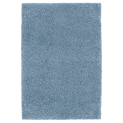 A blue IKEA ALMTJÄRN bath mat, rectangular and soft, made from recycled polyester, offering comfort and absorbency.
