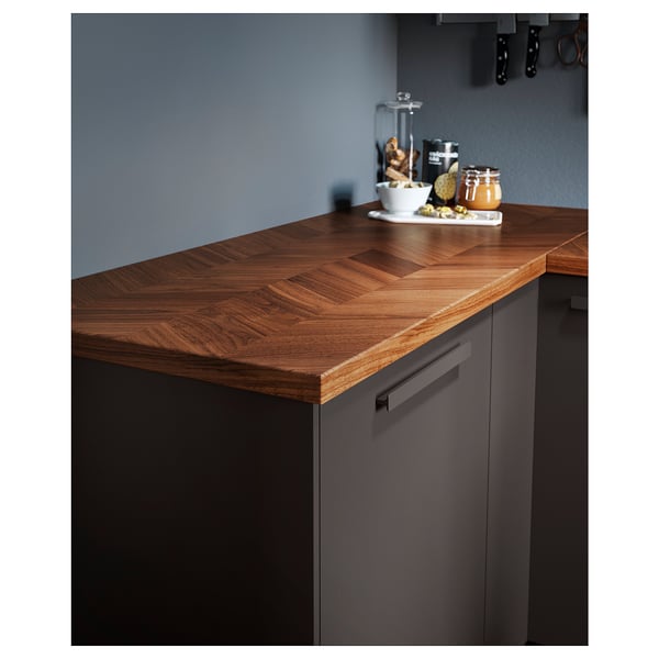 Wooden kitchen counter, BARKABODA model, in warm brown, featuring a chevron design, supported by dark cupboards.