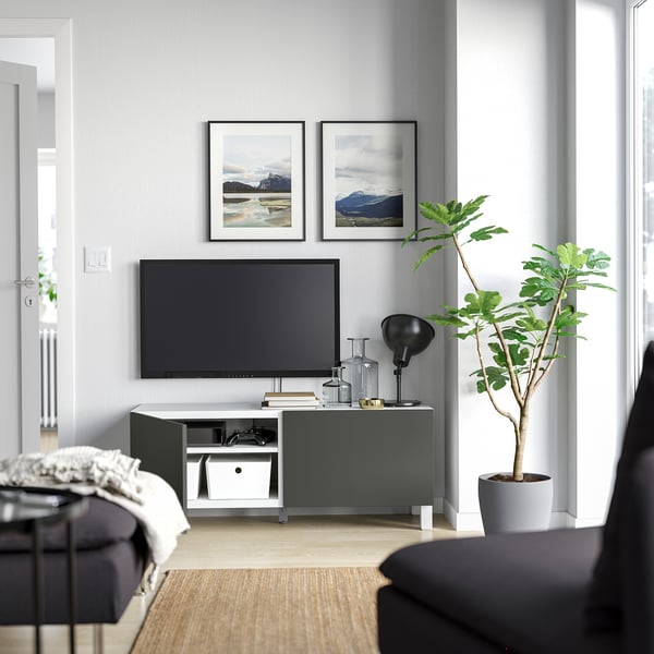 Modern living room: grey walls, tv stand, plant, couch, lamp.