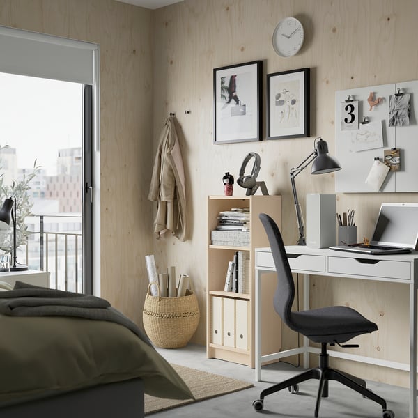 Wooden BILLY bookcase in room with lamp, laptop, chair, and coat. Holds books, basket, and near clock, pictures.