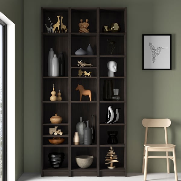 Bookcase with decor against green wall.