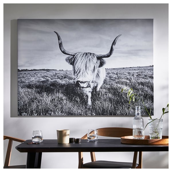 Dining room with bulls head painting, table, glasses, and candle.