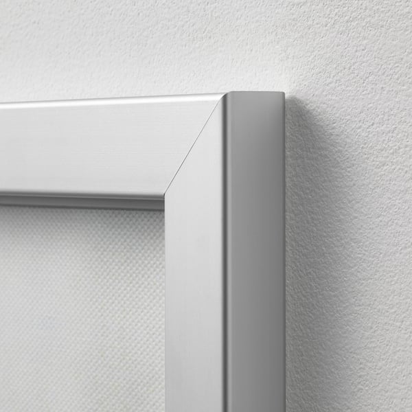 Close-up of corner details of a sleek, modern silver picture frame against a white wall. High-quality finish and clean lines.