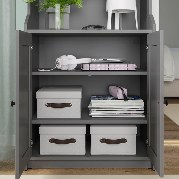 Open closet with white textiles, headphones, and a plant.