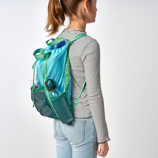 A child wears a blue-green backpack with mesh pockets and drawstring closure, identified by BLÅVINGAD. Adjustable straps fit securely.