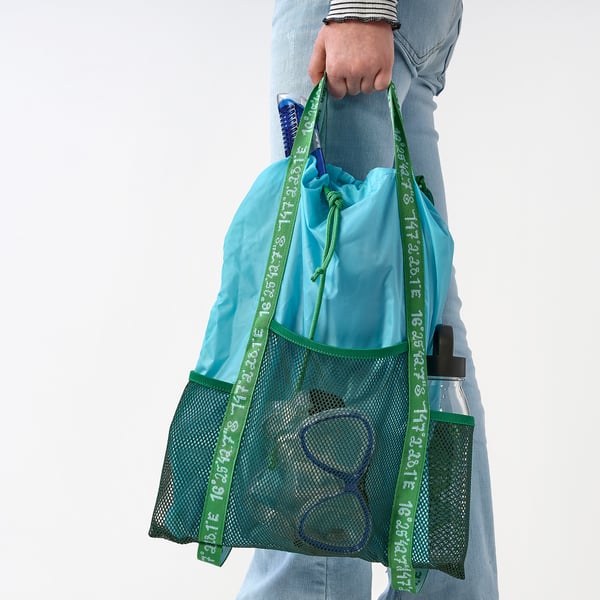 Person with BLÅVINGAD mesh backpack, featuring large and small pockets for outdoor use.