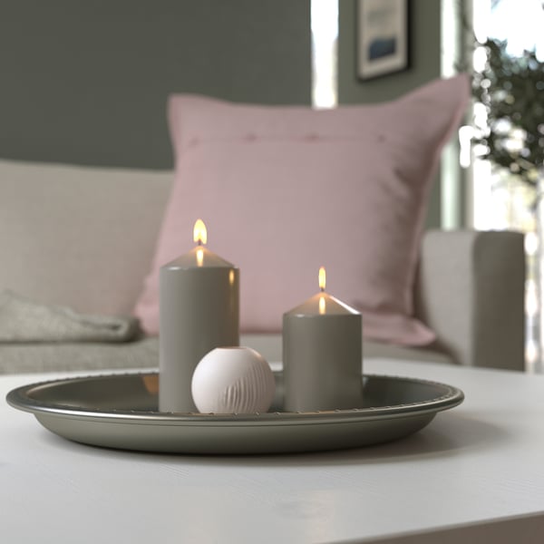 Grey candle dish with two lit candles and a decorative stone, enhancing room ambiance.