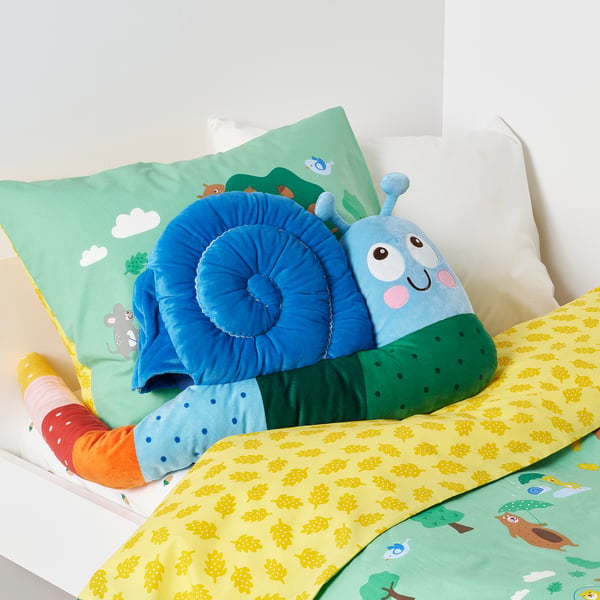 Snail-shaped kids pillow with blue and green plush, yellow and green leafy bedding, providing soft support and comfort.