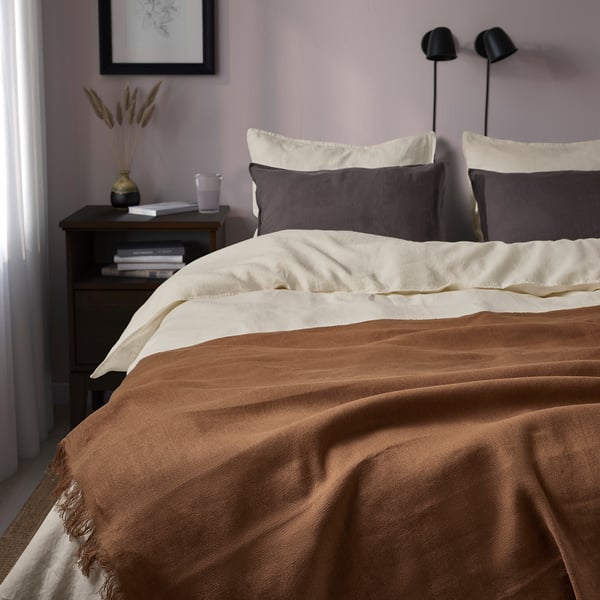 Brown throw blanket, grey pillows, bedside table, plants, art.