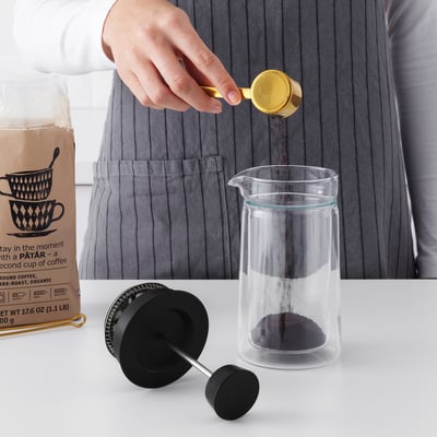 Pouring grounds into glass EGENTLIG coffee maker.