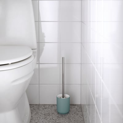 Minimalist bathroom with white toilet, blue brush holder & grey brush.