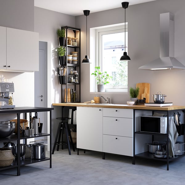 Modern kitchen with white cabinets, black shelves, wooden countertop, stainless steel appliances, and potted plants.