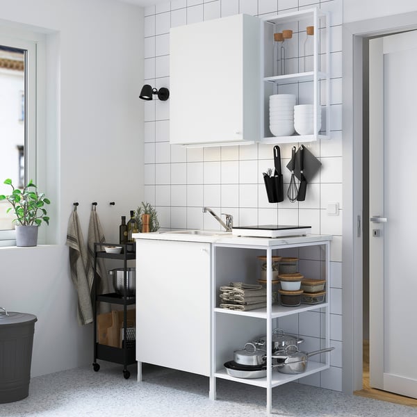 White ENHET kitchen set with marble top, sink, & cabinets. Minimalist, organised with a small plant.