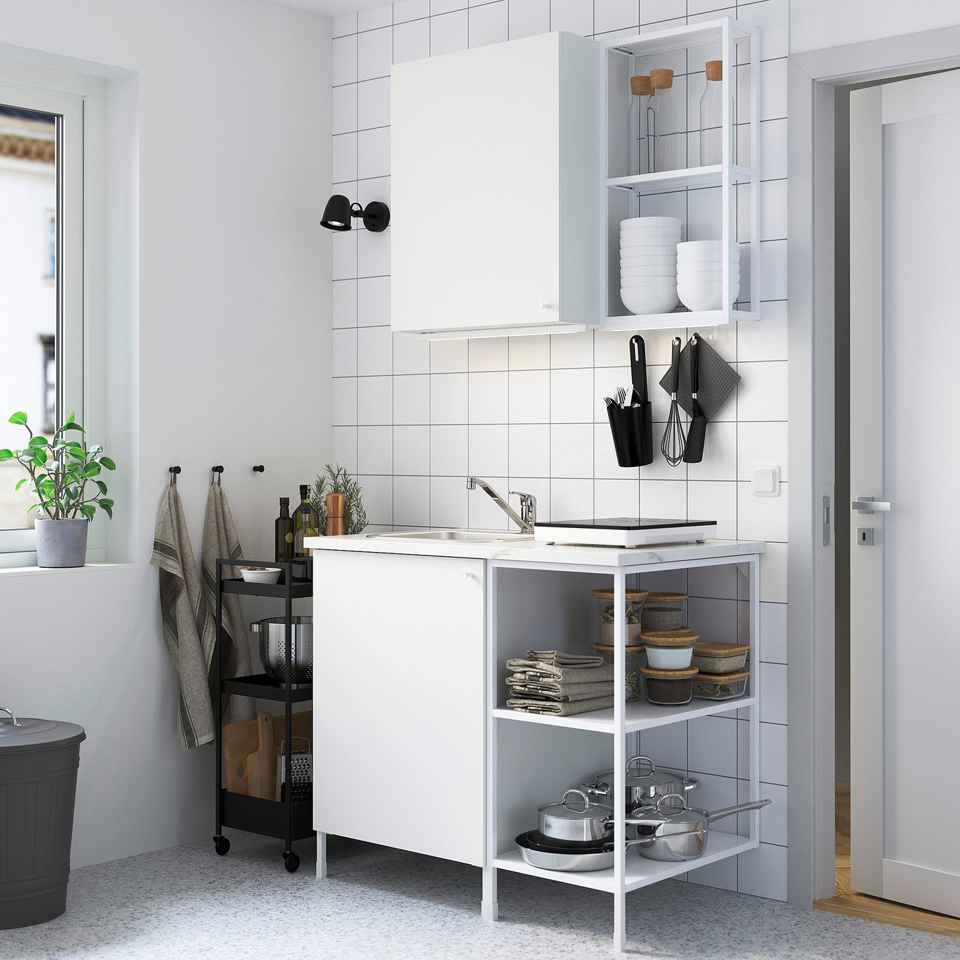White ENHET kitchen set with marble top, sink, & cabinets. Minimalist, organised with a small plant.