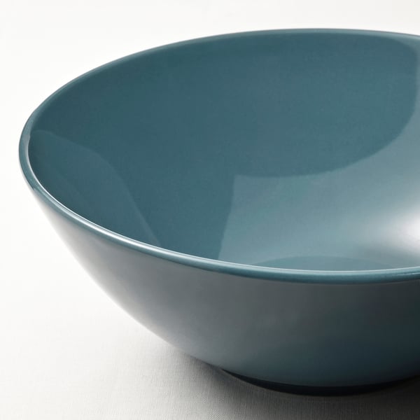 Close-up of a large, smooth, light blue bowl with a glossy interior on a plain surface.
