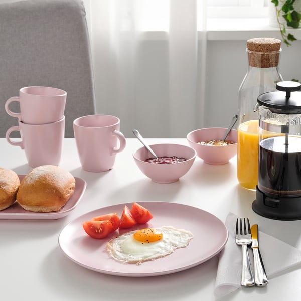 Pink kitchenware with breakfast items and coffee press.