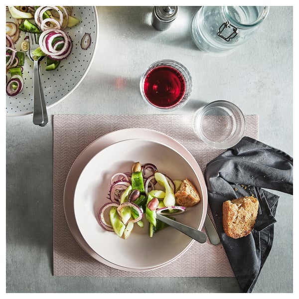 Top view of a grey table setting with FÄRGKLAR stoneware plates, cutlery, and glasses.