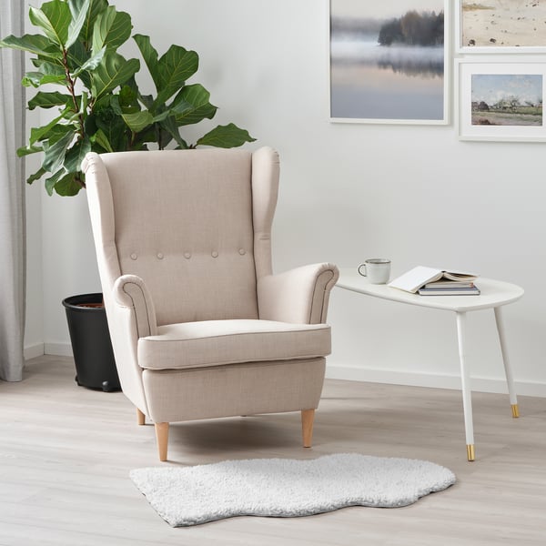 Cosy FÅRDRUP white rug under armchair by white side table & plant.