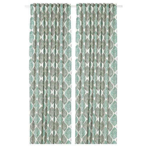 Green patterned curtains hang side-by-side, featuring a leafy design. Made of linen and cotton, they create a cosy atmosphere with natural texture.
