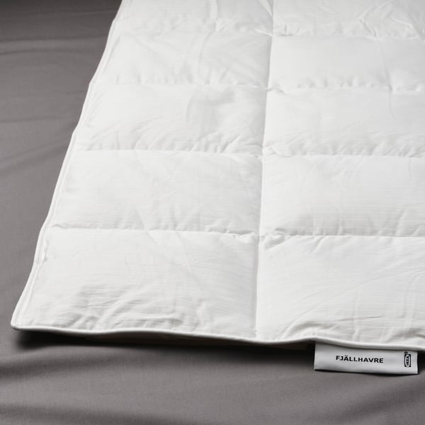 A neatly arranged white fjällräven duvet on a bed, showcasing its luxurious, super-fluffy texture and box-stitch pattern for even warmth.