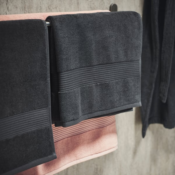 Three black towels with striped borders hang neatly on a rack, showcasing their soft, textured cotton material.