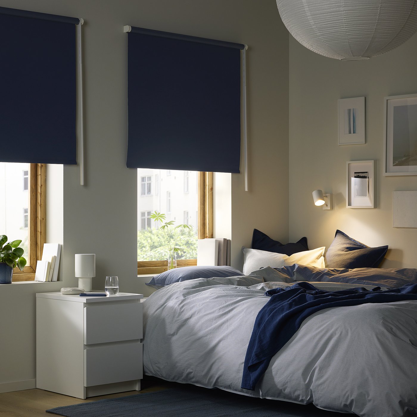Blue-stripe bed under navy blinds; city view window.