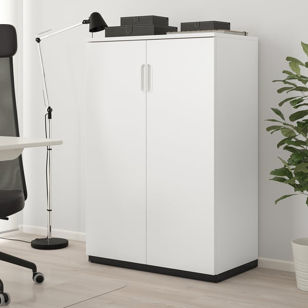White GALANT cabinet with 2 doors, particleboard, next to chair & lamp.