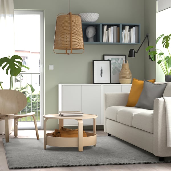 Modern living room with grey rug, light wood, grey sofa & decor.