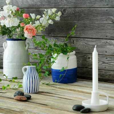 Wooden background with three vases of flowers & candle, natural decor.