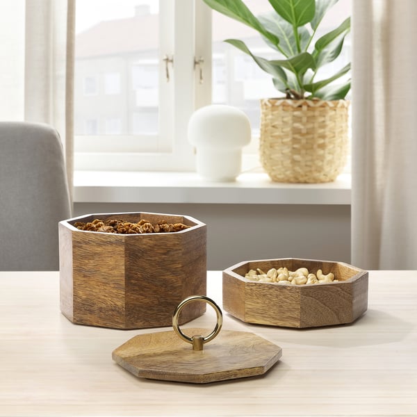 Wooden GOKVÄLLÅ container set with lids on light table, holding snacks, near plant.