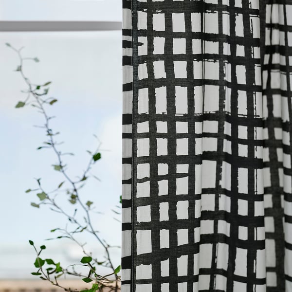 Striped curtains hang by a window, letting soft light through. A plant adds greenery to minimalist decor.