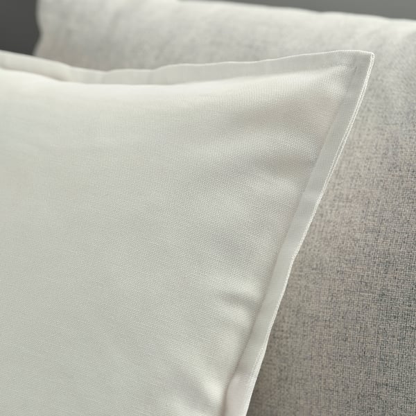 Close-up of soft, white cotton cushion cover with neat stitching, showcasing quality texture and zip detail.