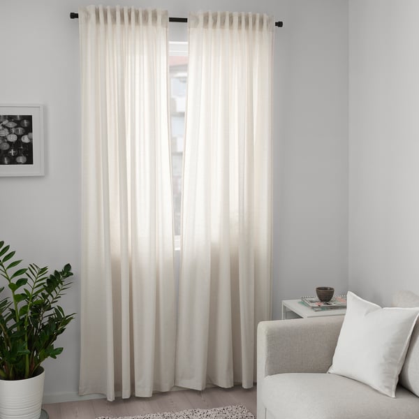 White cotton curtains beside window with plant and chair.