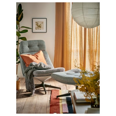 Cosy living room with HAVBERG footstool, colourful rug, and armchair by window.